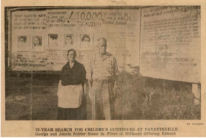 Mr. and Mrs. George Sodder standing in front of the billboard looking for their missing children.